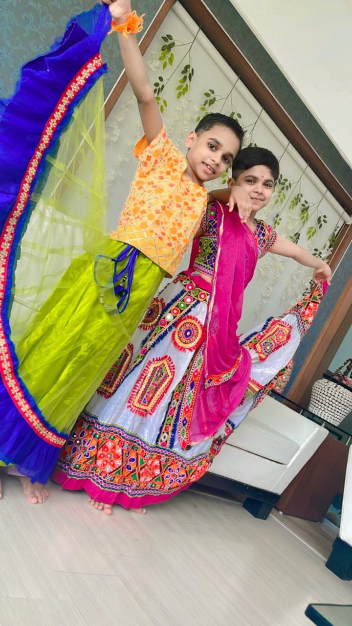 Two girls striking a dance pose in colourful skirts