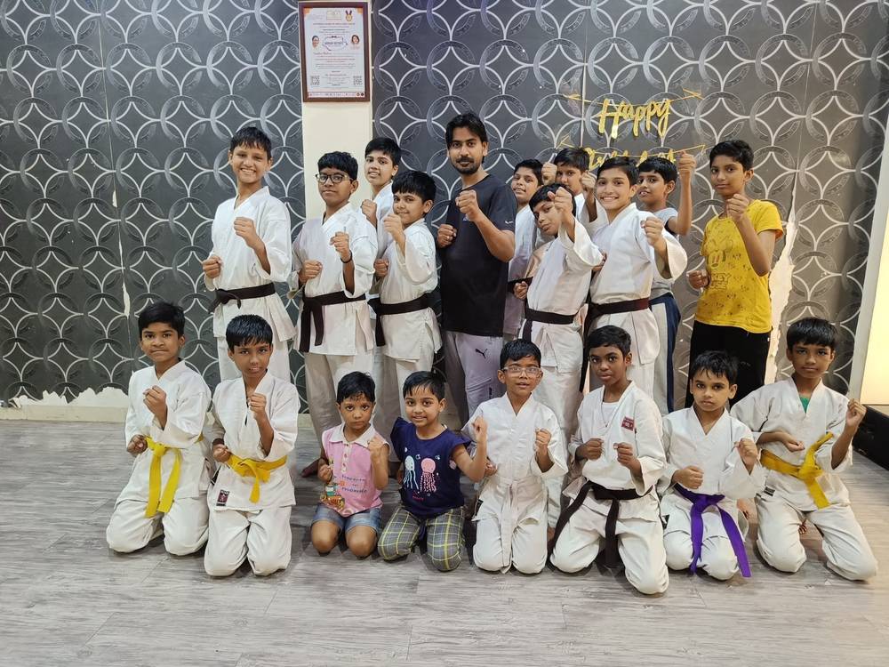 Karate students at Shiv Karmsthali celebrating together in class, wearing coloured belts
