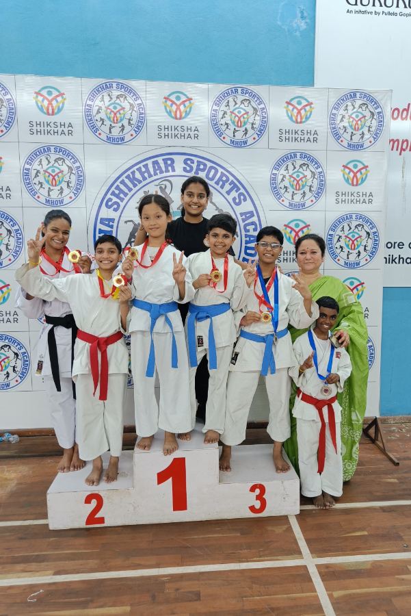Girls on a competition podium in karate uniforms with medals