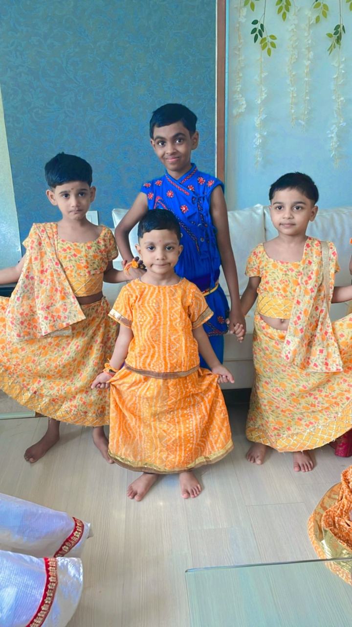 Three children in orange and blue festival costumes