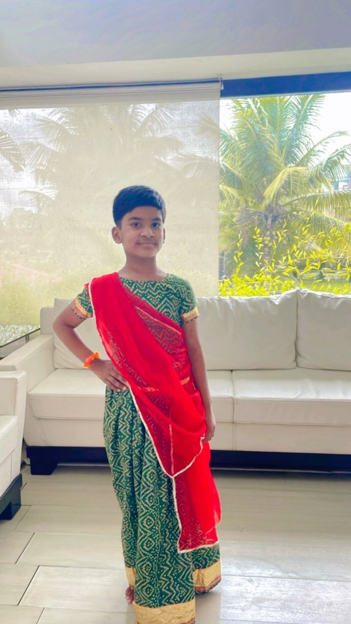 Child posing in a traditional red and green outfit